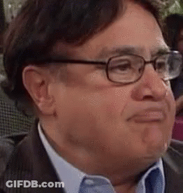 A Man In A Suit And Tie Is Wearing Glasses And Making A Funny Face . GIF