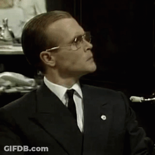 A Man In A Suit And Tie Is Wearing Glasses GIF
