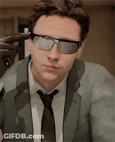 A Man In A Suit And Tie Is Wearing Sunglasses And A Tie . GIF