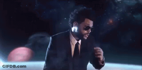 A Man In A Suit And Tie Is Wearing Sunglasses And Dancing On A Stage . GIF