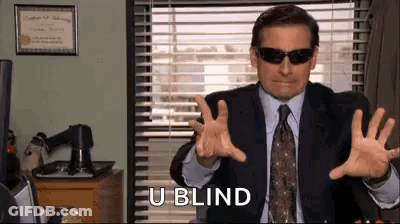 A Man In A Suit And Tie Is Wearing Sunglasses And Making A Gesture . GIF