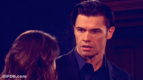 A Man In A Suit And Tie Looks At A Woman GIF