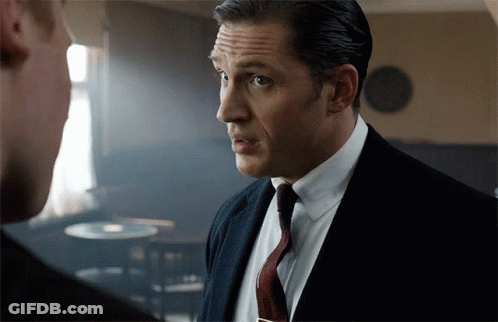A Man In A Suit And Tie Looks At Another Man GIF