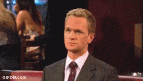 A Man In A Suit And Tie Looks At Something GIF