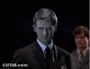 A Man In A Suit And Tie Looks At The Camera GIF