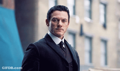 A Man In A Suit And Tie Looks At The Camera GIF