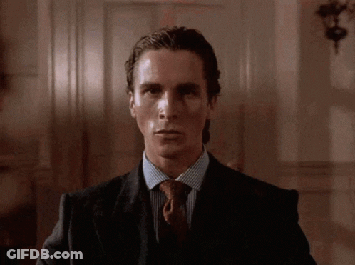 A Man In A Suit And Tie Looks At The Camera With A Serious Look On His Face GIF