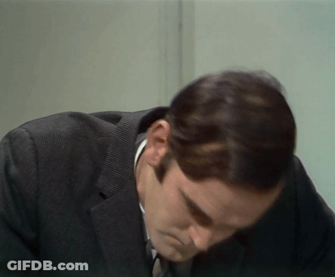A Man In A Suit And Tie Looks Down GIF