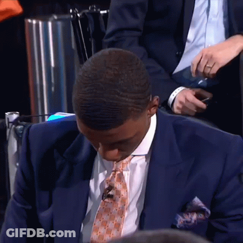 A Man In A Suit And Tie Looks Down GIF