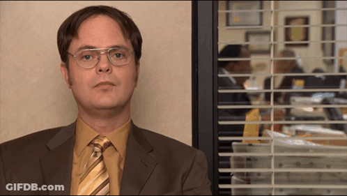 A Man In A Suit And Tie Looks Out A Window GIF