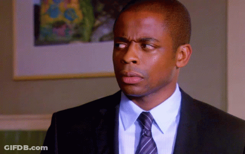 A Man In A Suit And Tie Looks To His Left GIF