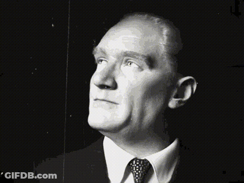 A Man In A Suit And Tie Looks Up At The Sky GIF