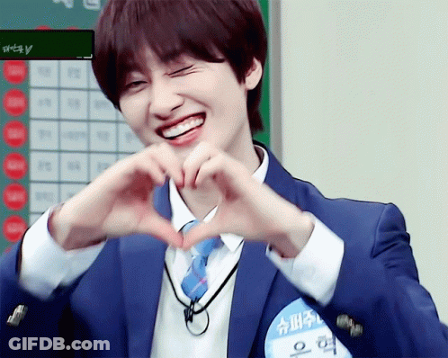 A Man In A Suit And Tie Making A Heart With His Hands GIF
