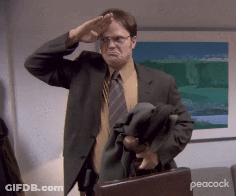 A Man In A Suit And Tie Salutes While Holding A Briefcase With Peacock Written On The Bottom GIF