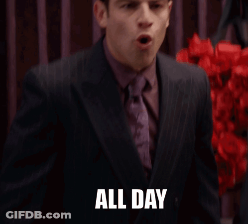 A Man In A Suit And Tie Says " All Day " In Front Of Red Flowers GIF