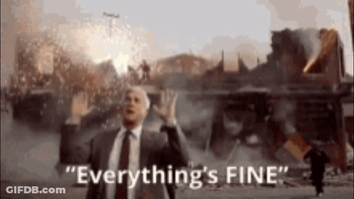 A Man In A Suit And Tie Says " Everything 'S Fine " In Front Of A Burning Building GIF