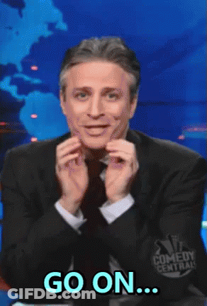 A Man In A Suit And Tie Says Go On In Front Of A Comedy Central Logo GIF