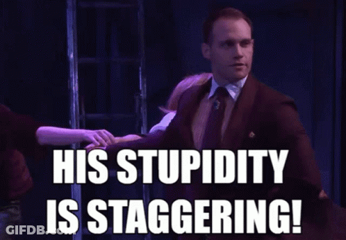 A Man In A Suit And Tie Says His Stupidity Is Staggering In Front Of A Group Of People GIF