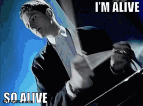 A Man In A Suit And Tie Says I 'M Alive GIF
