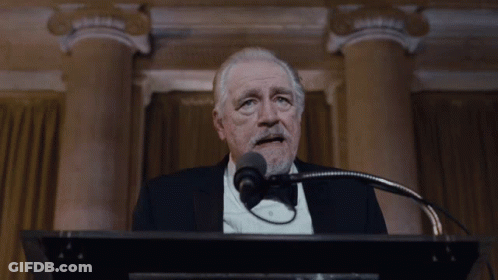 A Man In A Suit And Tie Says " I 'M Back " GIF