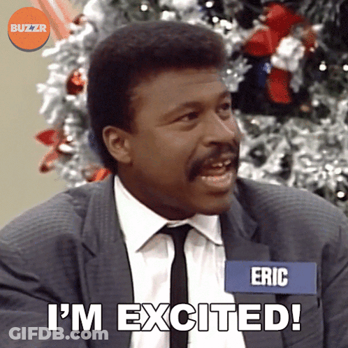 A Man In A Suit And Tie Says I 'M Excited In Front Of A Christmas Tree GIF