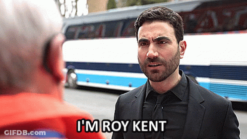 A Man In A Suit And Tie Says I 'M Roy Kent In Front Of A Bus GIF
