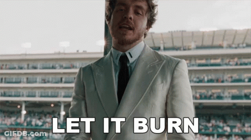 A Man In A Suit And Tie Says Let It Burn In Front Of A Stadium GIF