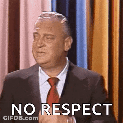 A Man In A Suit And Tie Says " No Respect " In Front Of A Curtain GIF