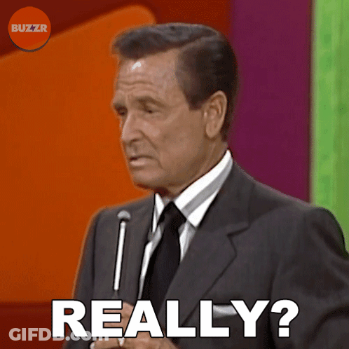 A Man In A Suit And Tie Says " Really " In Front Of A Microphone GIF