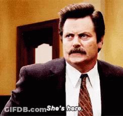 A Man In A Suit And Tie Says She 'S Here . GIF