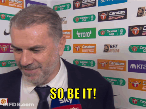 A Man In A Suit And Tie Says So Be It In Front Of A Wall Of Advertisements GIF