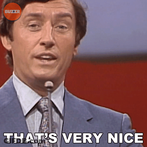 A Man In A Suit And Tie Says " That 'S Very Nice " In Front Of A Microphone GIF