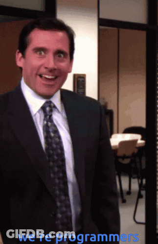 A Man In A Suit And Tie Says We 'Re Programmers In Blue Letters GIF