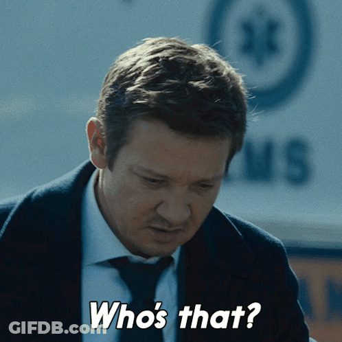 A Man In A Suit And Tie Says " Who 'S That " In Front Of An Ambulance GIF