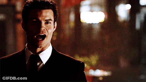 A Man In A Suit And Tie Screams With His Mouth Open GIF