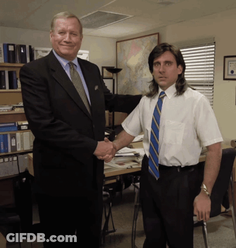 A Man In A Suit And Tie Shakes Hands With Another Man In A White Shirt And Tie GIF