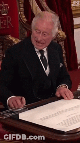 A Man In A Suit And Tie Signing A Document GIF