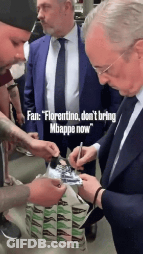 A Man In A Suit And Tie Signing A Piece Of Paper GIF