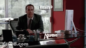 A Man In A Suit And Tie Sits At A Desk With A Sign On It That Says ' Really ? ' GIF
