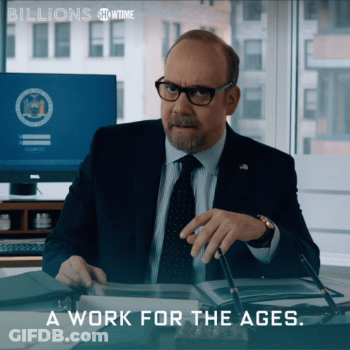 A Man In A Suit And Tie Sits At A Desk With The Words " A Work For The Ages " Above Him GIF
