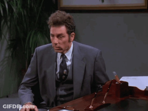 A Man In A Suit And Tie Sits At A Desk With The Words " I Don 'T Even Really Work Here " Above Him GIF