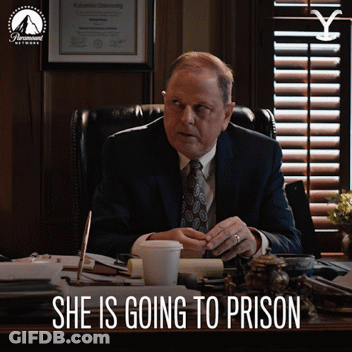 A Man In A Suit And Tie Sits At A Desk With The Words She Is Going To Prison Written Below Him GIF