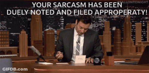 A Man In A Suit And Tie Sits At A Desk With The Words Your Sarcasm Has Been Duly Noted And Filed GIF