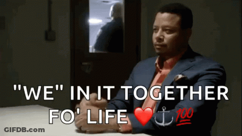 A Man In A Suit And Tie Sits At A Table With The Words " We " In It Together Fo ' Life GIF
