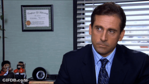 A Man In A Suit And Tie Sits In Front Of A Framed Certificate Of Authentication GIF