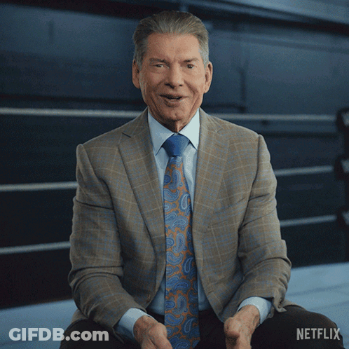 A Man In A Suit And Tie Sits In Front Of A Netflix Logo GIF