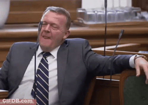 A Man In A Suit And Tie Sits In Front Of A Sign That Says Statsministeren On It GIF