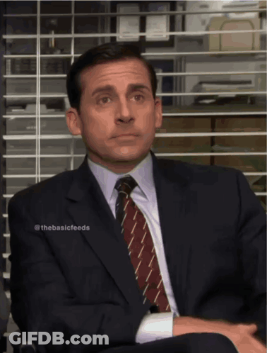 A Man In A Suit And Tie Sits In Front Of A Window GIF