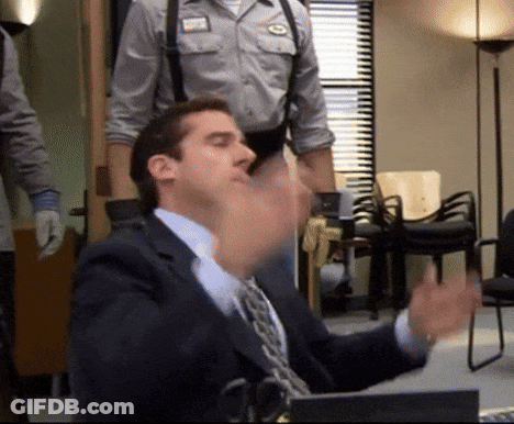 A Man In A Suit And Tie Sitting At A Desk GIF