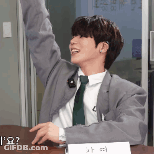 A Man In A Suit And Tie Sitting At A Desk GIF